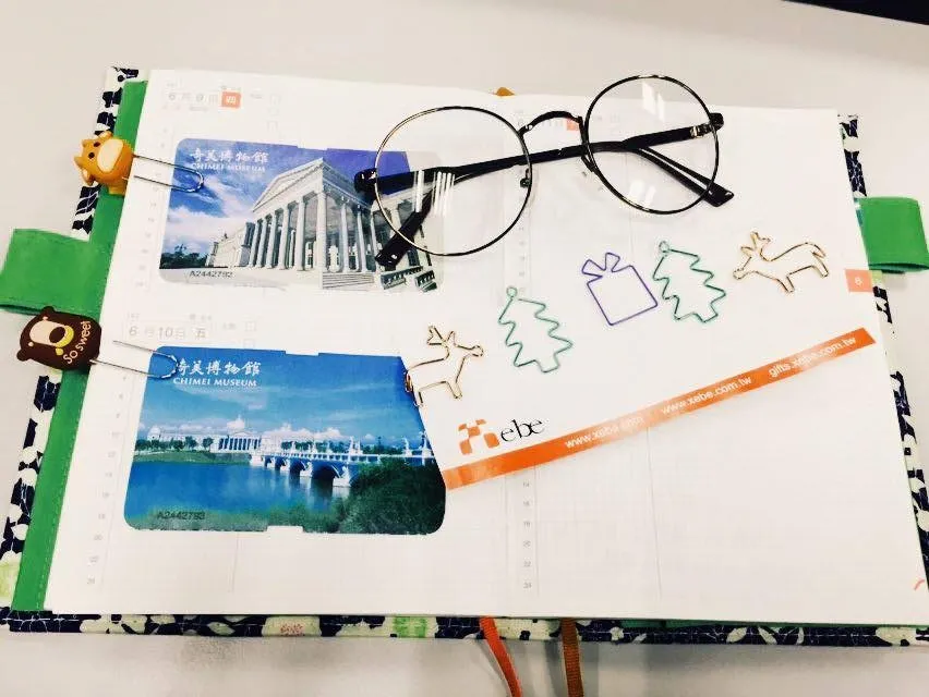 The glasses are placed on the notebook with a custom paper clip next to them