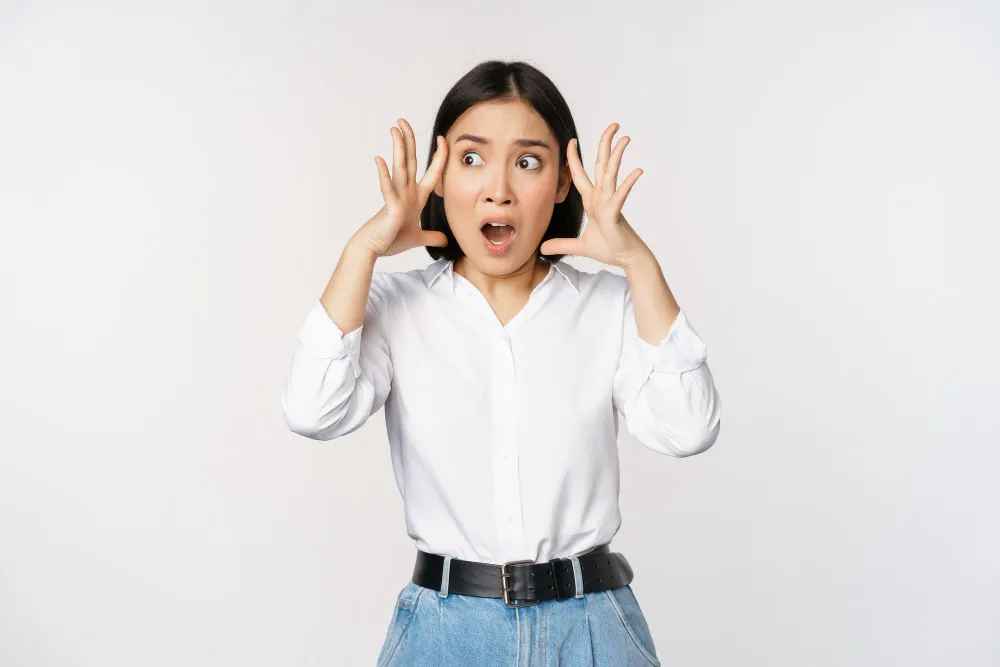 Image of shocked anxious asian woman in panic holding hands on head and worryin