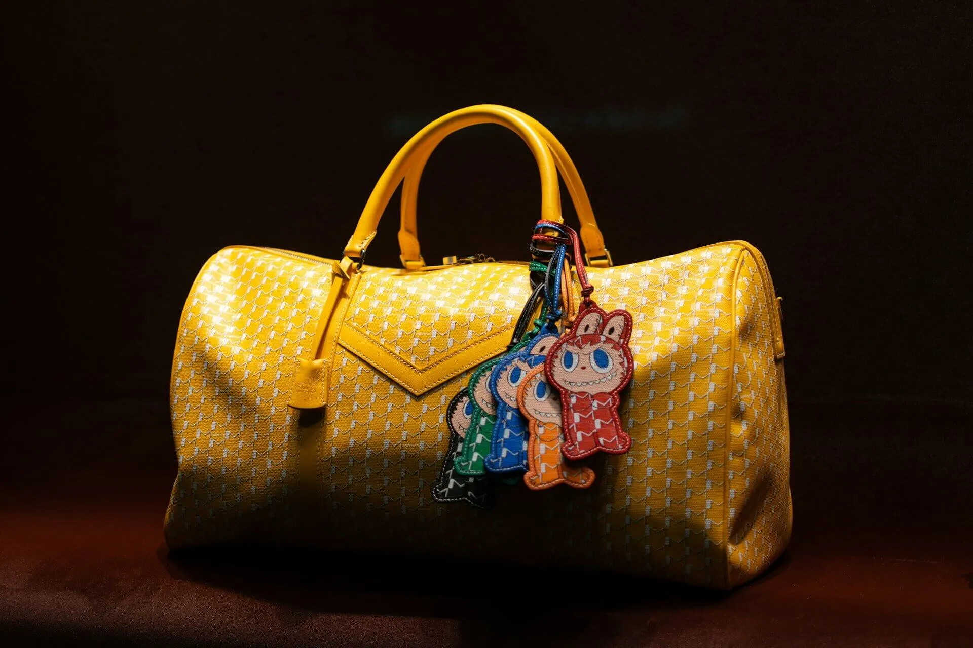 Yellow patterned duffel bag with colorful charms